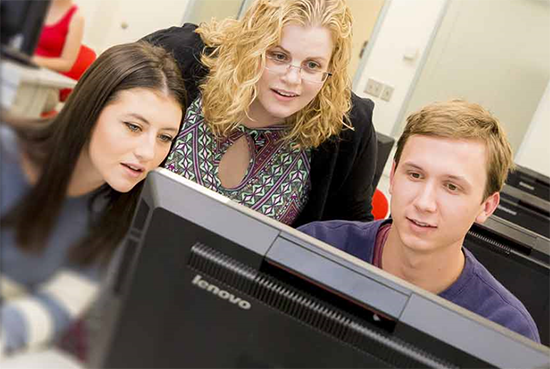 Two students and instructor look at computer monitor